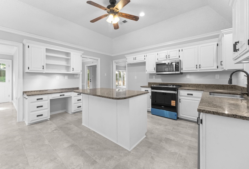 Modern kitchen featuring white cabinetry, granite countertops, a central island, stainless steel appliances, and tile flooring