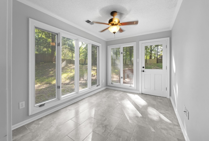 Room with light gray walls, an array of four casement windows, and a glass-paneled exterior door