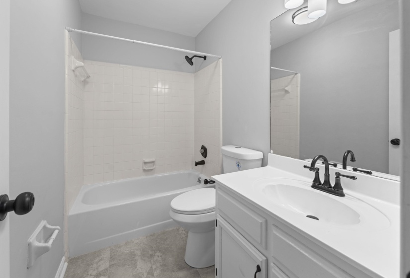 Bathroom featuring a white vanity with integrated sink, black fixtures, and a spacious mirror
