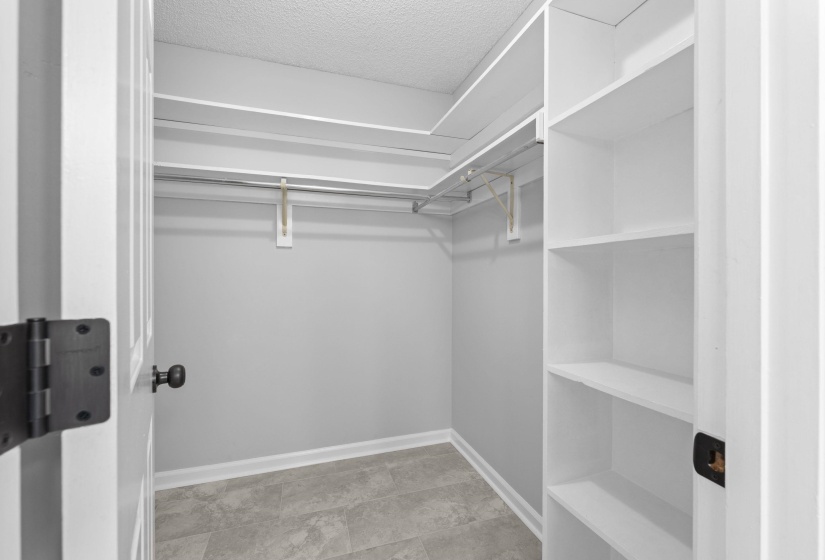 Walk-in closet featuring built-in shelving, multi-level hanging rods, and textured flooring