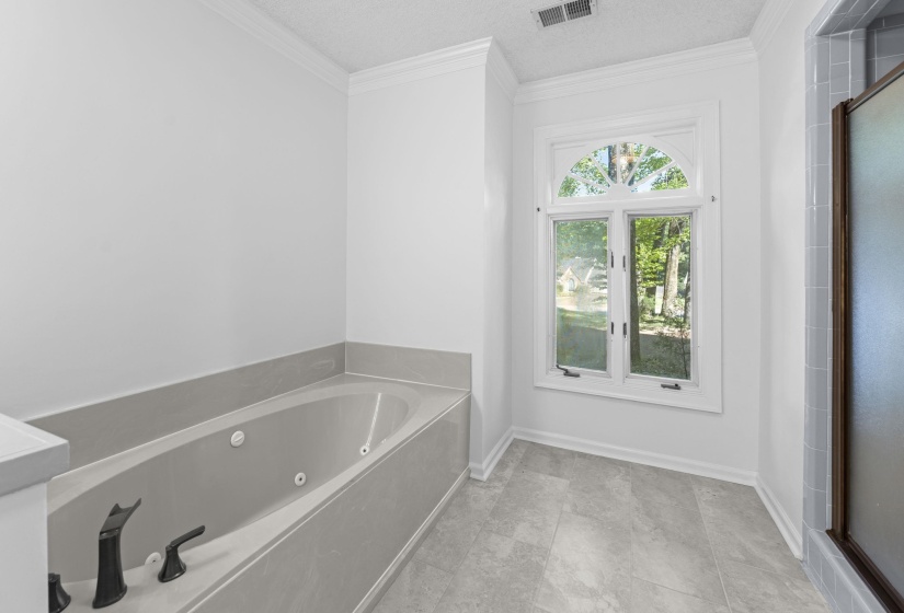 Integrated soaking tub with black fixtures, set within a light gray surround