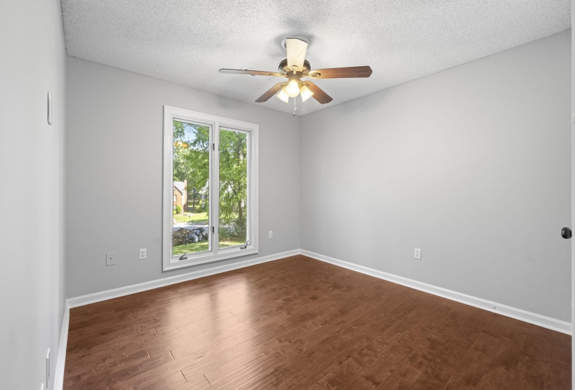 Interior room featuring wood-finish flooring, light gray wall paint, and white baseboards