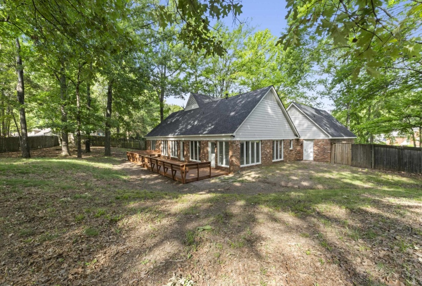 Expansive rear yard featuring mature trees, a multi-level wood deck, and a full privacy fence