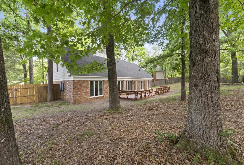 Rear exterior featuring a brick and white siding facade, a dark shingle roof, a wooden deck, and a fenced perimeter