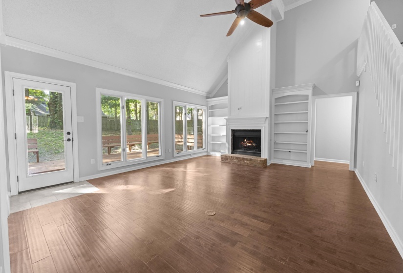 Vaulted ceiling great room featuring wood-finish flooring and a fireplace with brick hearth