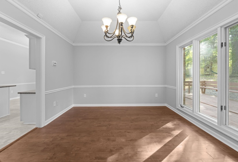 Dining area with vaulted ceiling and wood-finish flooring