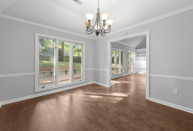 Spacious room featuring wood-finish flooring, a contemporary ceiling fixture, and a large triple window overlooking the exterior