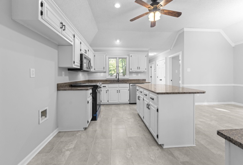 Spacious kitchen featuring white cabinetry, dark stone-finish countertops, and a central island