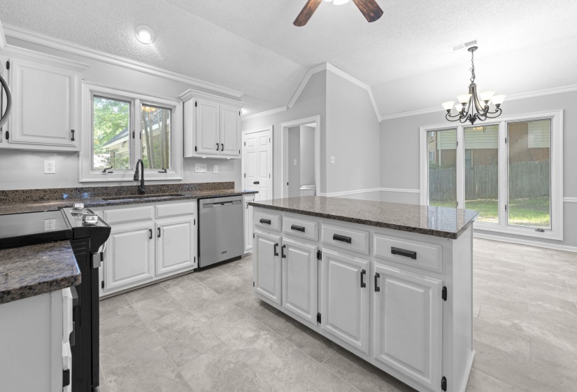 Kitchen featuring white cabinetry with dark hardware, granite countertops, stainless steel appliances, a center island, and tile flooring