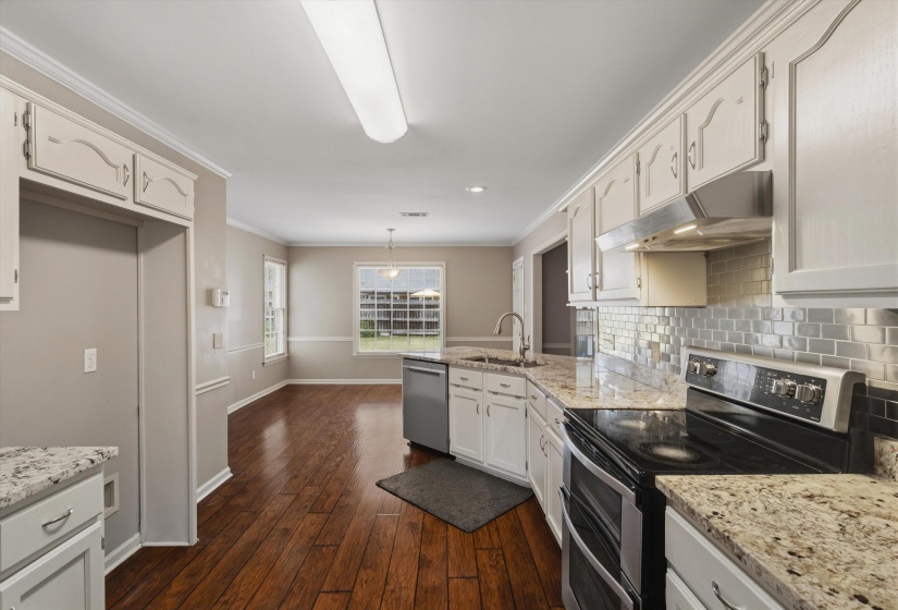 Kitchen featuring white cabinetry, light-toned countertops, a stainless steel dishwasher, and a black electric range with a stainless steel vent hood