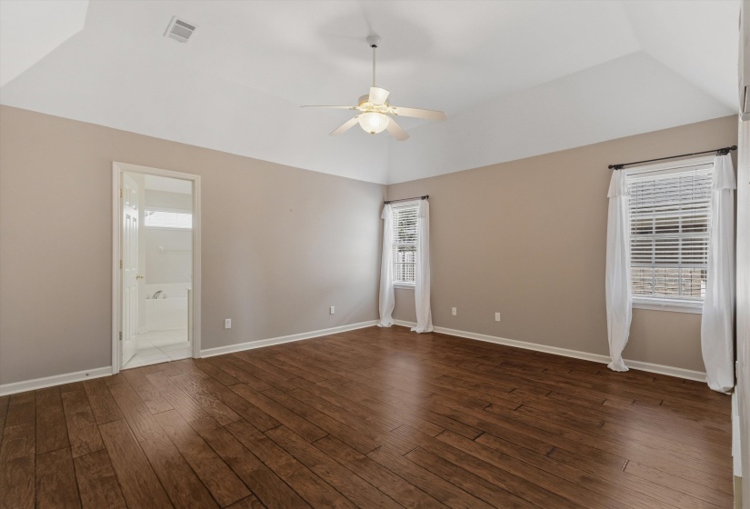 Spacious room featuring vaulted ceilings, wood-finish flooring, and neutral wall tones