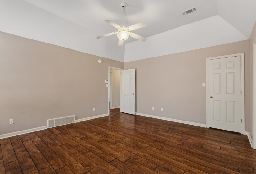 Spacious room featuring wood-finish flooring, a vaulted ceiling, and neutral wall tones