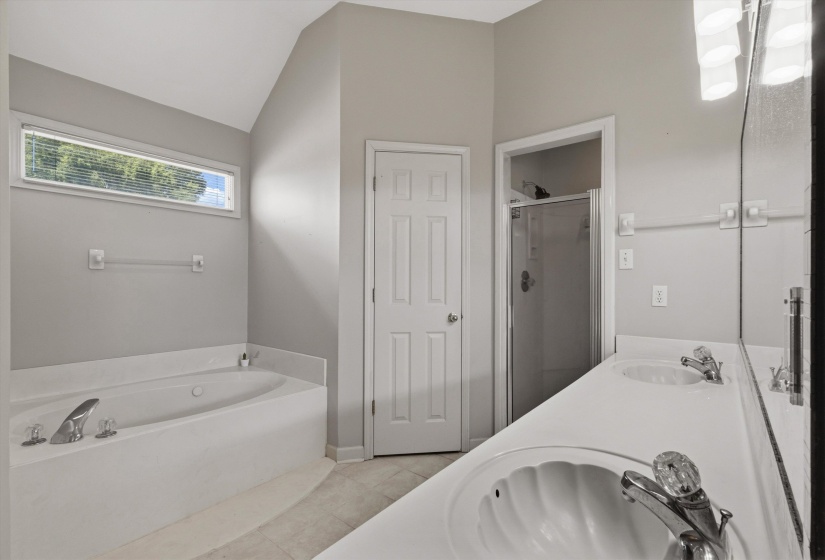 Bathroom featuring a built-in soaking tub, a dual vanity with integrated sinks, and a glass-enclosed shower