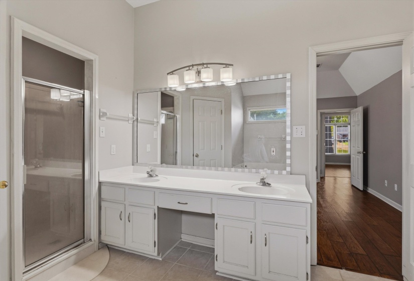 Bathroom featuring a dual vanity with white cabinetry, integrated sinks, and a large wall-mounted mirror