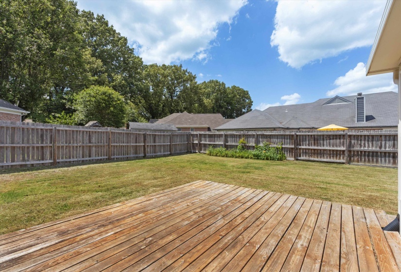 Expansive backyard featuring a natural wood deck, verdant lawn, and perimeter wood privacy fencing