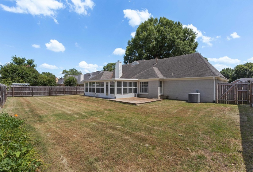 Expansive backyard featuring a screened-in porch with multiple windows, a wood deck, and a full perimeter wood fence