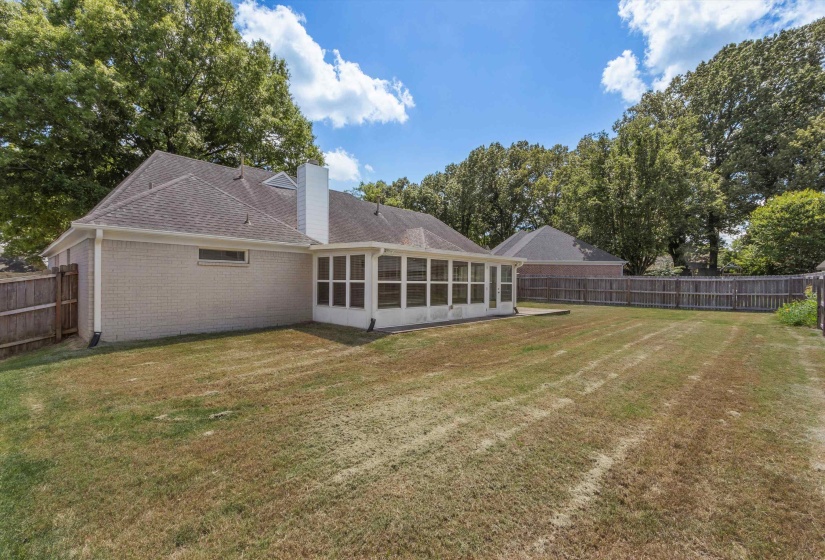 Expansive backyard featuring a screened porch and a wood privacy fence