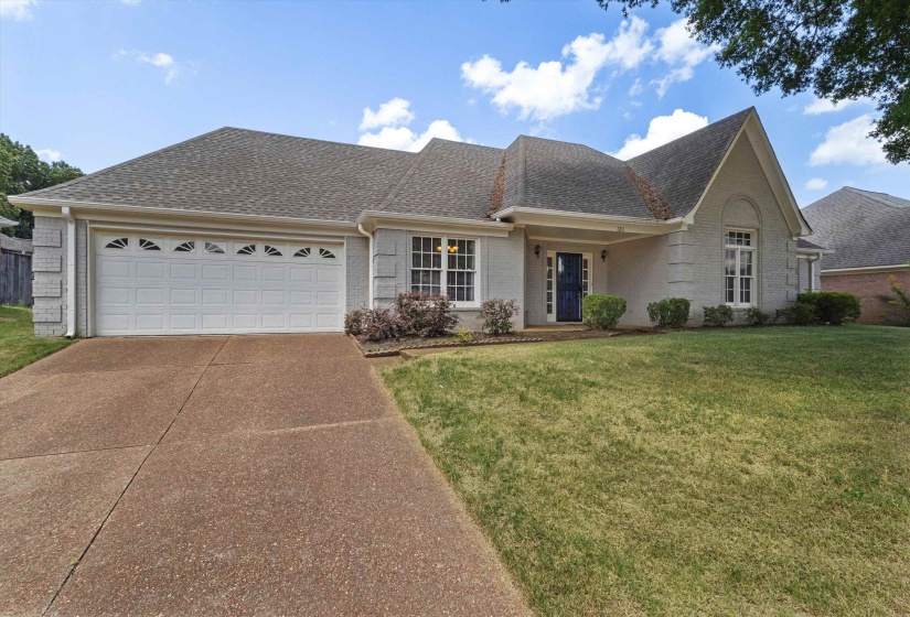 Ranch-style residence featuring a prominent two-car garage with decorative windows, a dark blue entry door with side lights, and a concrete driveway
