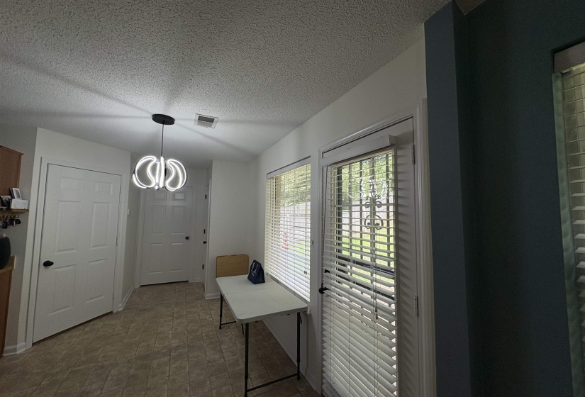 Entryway featuring a contemporary ceiling light fixture, two panel doors with black hardware, and tiled flooring