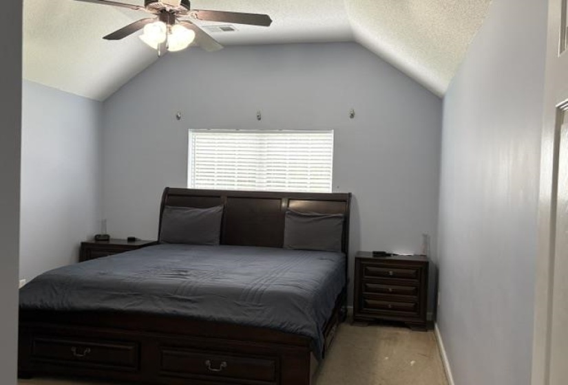 Vaulted ceilings with a ceiling fan light fixture, window with blinds, light blue wall paint, and carpeted flooring