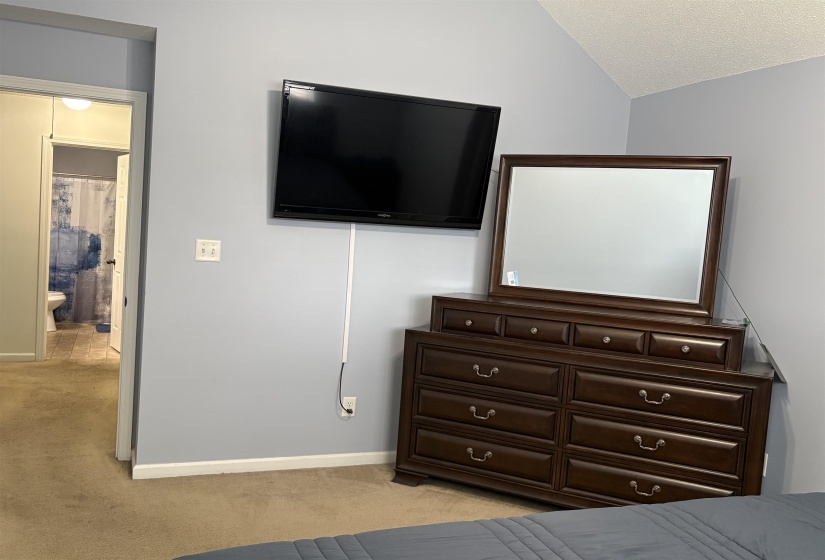 Carpeted room with a vaulted ceiling and light gray walls