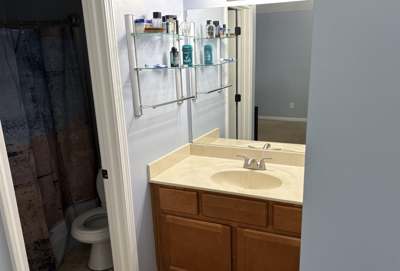 Bathroom featuring a wood-finish vanity with a beige countertop and integrated sink, chrome faucet, and a wall-mounted mirror