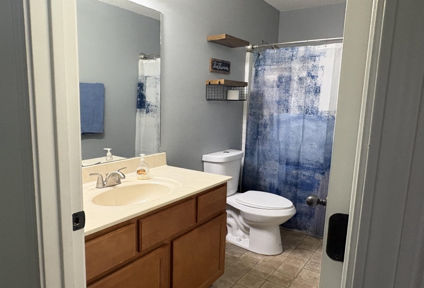Bathroom featuring a vanity with a cream-toned countertop and integrated sink, chrome faucet, wood-finish cabinetry, and a toilet