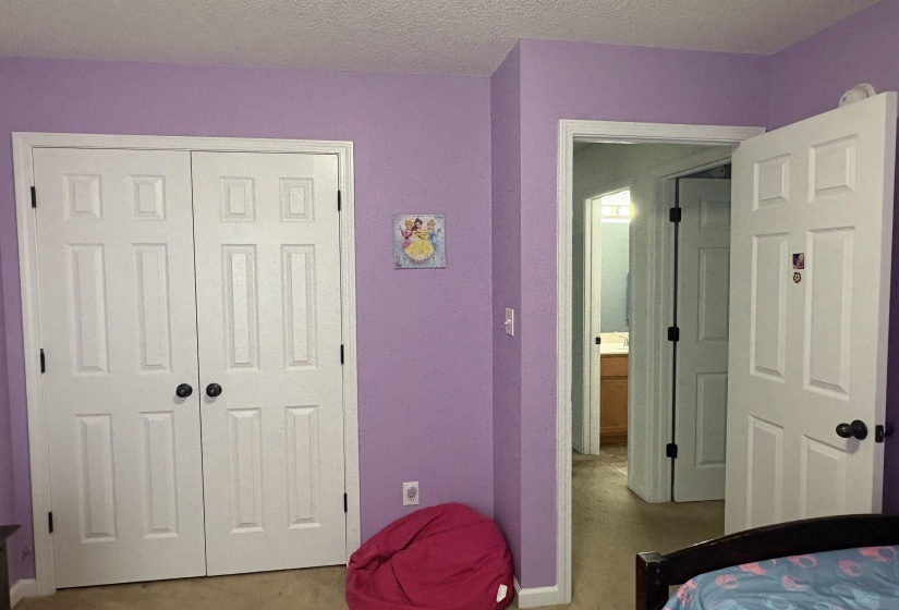 Room featuring two panel bi-fold doors with black hardware, an interior doorway with a solid core door, and wall-to-wall carpeting