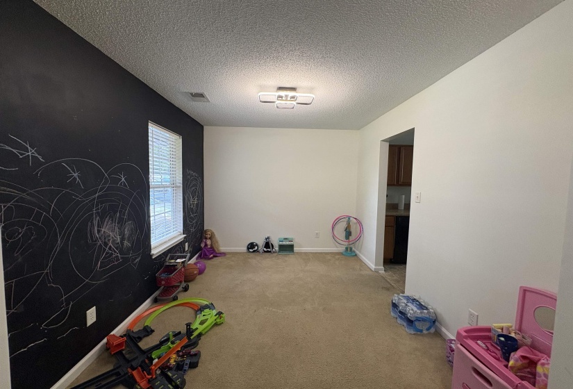 Spacious room with a chalkboard accent wall, textured ceiling, and carpeted flooring