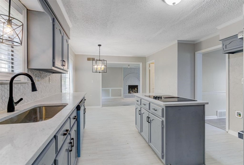 Kitchen featuring ornamental molding, a fireplace, a kitchen island, a textured ceiling, and gray cabinetry