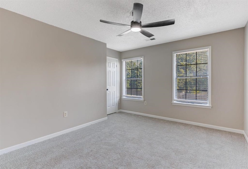 Empty room with light colored carpet, ceiling fan, and a textured ceiling