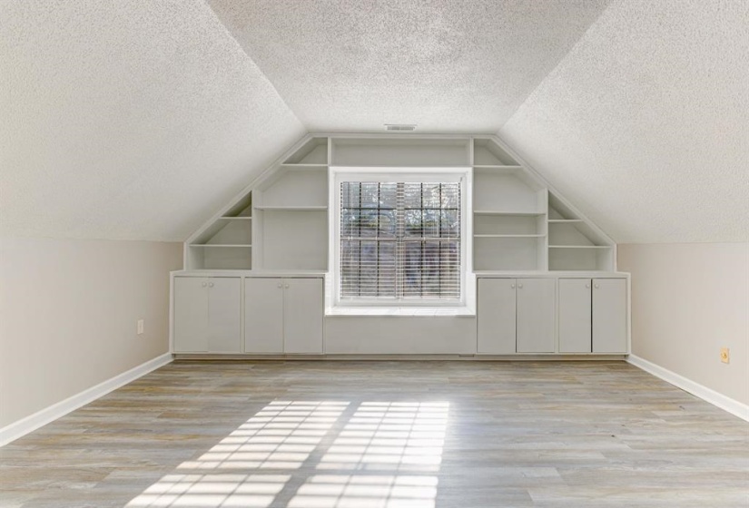 Bonus room featuring built in features, a textured ceiling, and light wood-style flooring