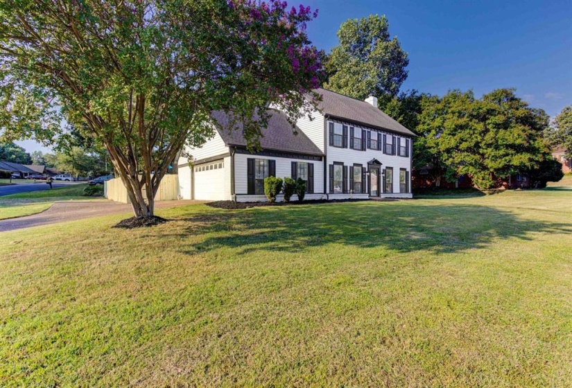 Colonial home featuring a front yard, a chimney, an attached garage, and driveway