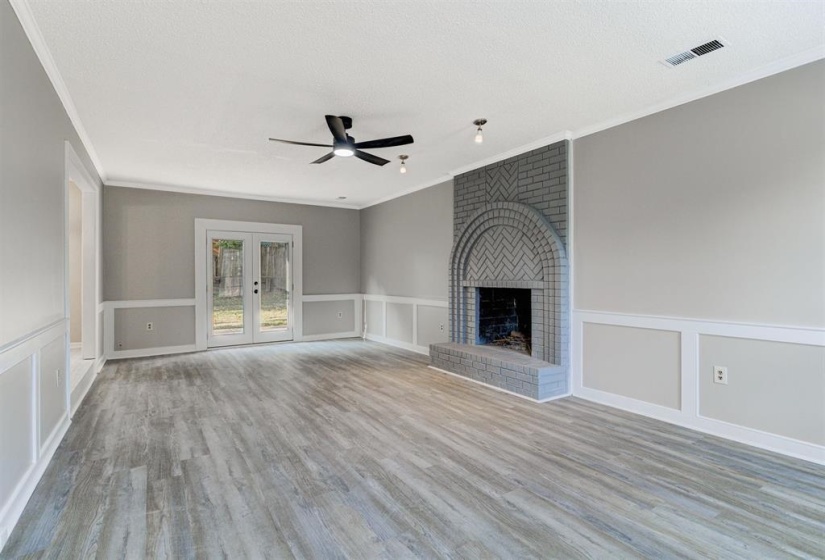 Unfurnished living room with a decorative wall, french doors, wainscoting, light wood-style flooring, and a ceiling fan