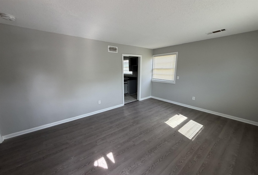 Spacious interior featuring wood-finish flooring, light gray wall paint, and white trim