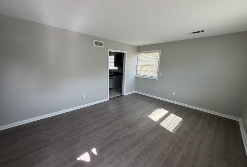 Spacious room featuring neutral gray walls and wood-finish flooring