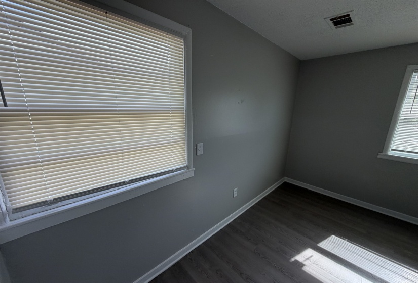 Room featuring dark wood-finish flooring, light gray wall paint, and white trim