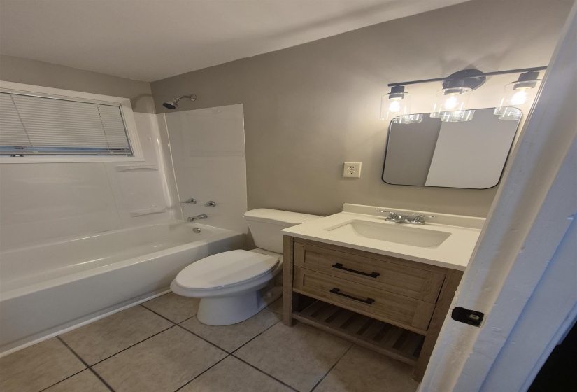 Bathroom featuring a single-basin vanity with a light wood-finish cabinet, a white countertop, and a rectangular mirror