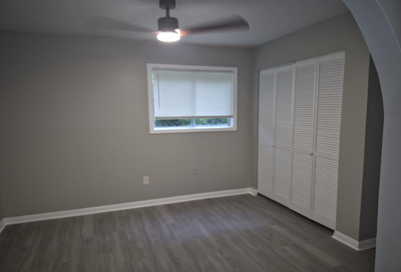 Room featuring light gray walls, wood-finish flooring, and white baseboards