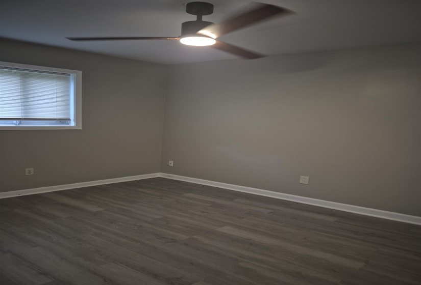 Room featuring light gray wall paint, wood-finish flooring, and white baseboards