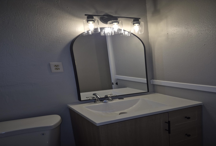 Modern bathroom vanity featuring a white integrated sink, chrome faucet, and wood-finish cabinetry