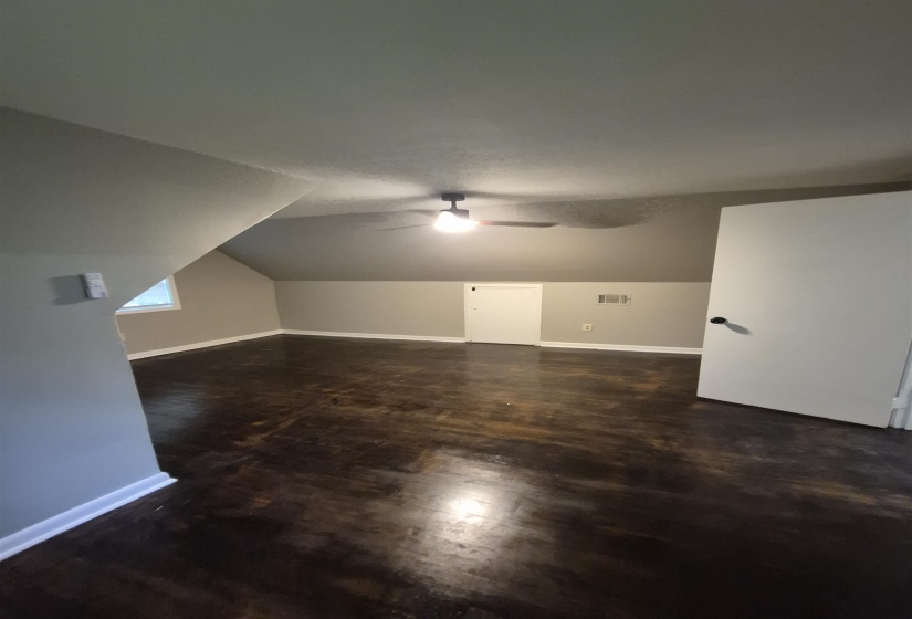 Room with dark wood-finish flooring, a sloped ceiling, and light-toned walls