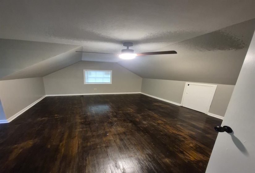 Attic space with sloped ceilings and dark wood-finish flooring
