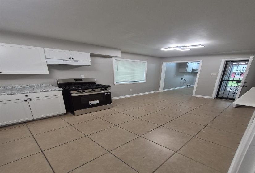 Kitchen featuring white cabinetry, speckled countertops, and a stainless steel gas range