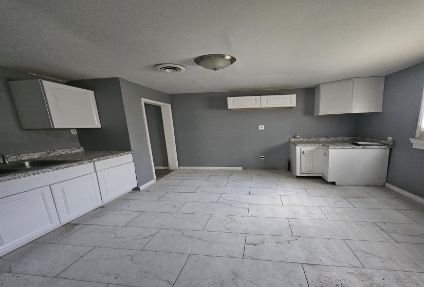 Kitchen featuring white shaker-style cabinetry, light-toned countertops, and a stainless steel sink