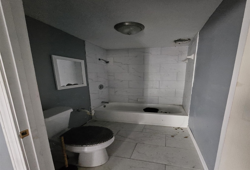 Bathroom featuring white subway tile shower surround, a white bathtub, and a white toilet