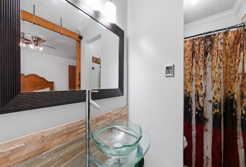 Bathroom vanity featuring a glass vessel sink with a chrome faucet. Some features are AI-enhanced.