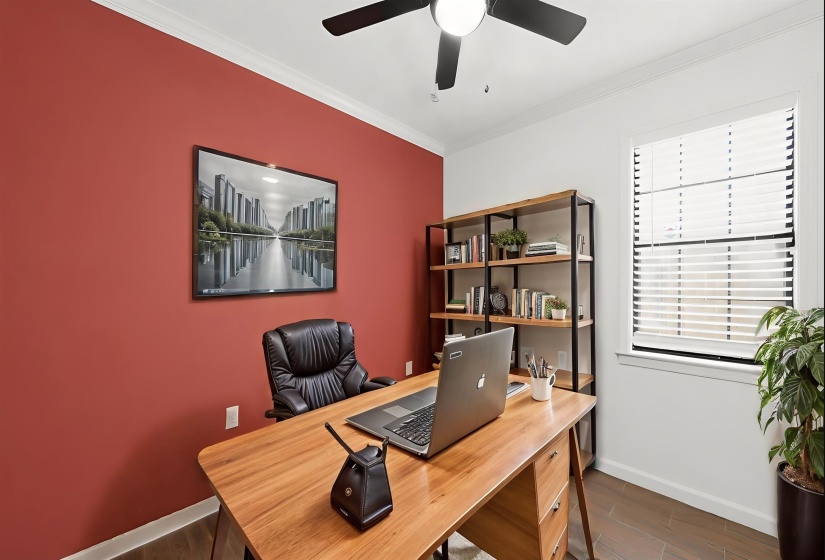 Bedroom 3 or Home office, featuring a prominent accent wall, crown molding, wood-finish flooring, and a ceiling fan with integrated lighting. Some features are AI-enhanced.