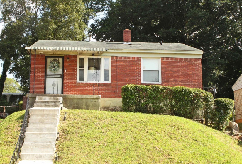 Red brick exterior with a pitched roof, front entry awning, and a security screen door