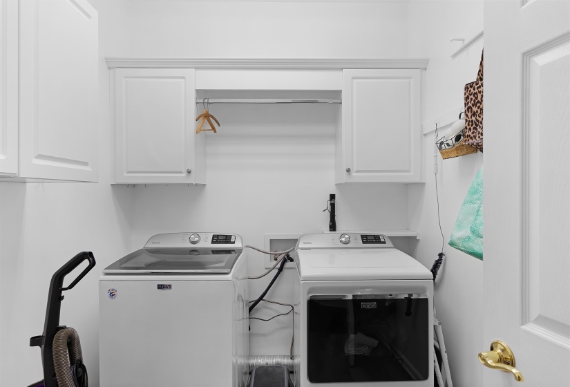 Dedicated laundry space featuring white cabinetry, a built-in hanging rod, and bright white walls
